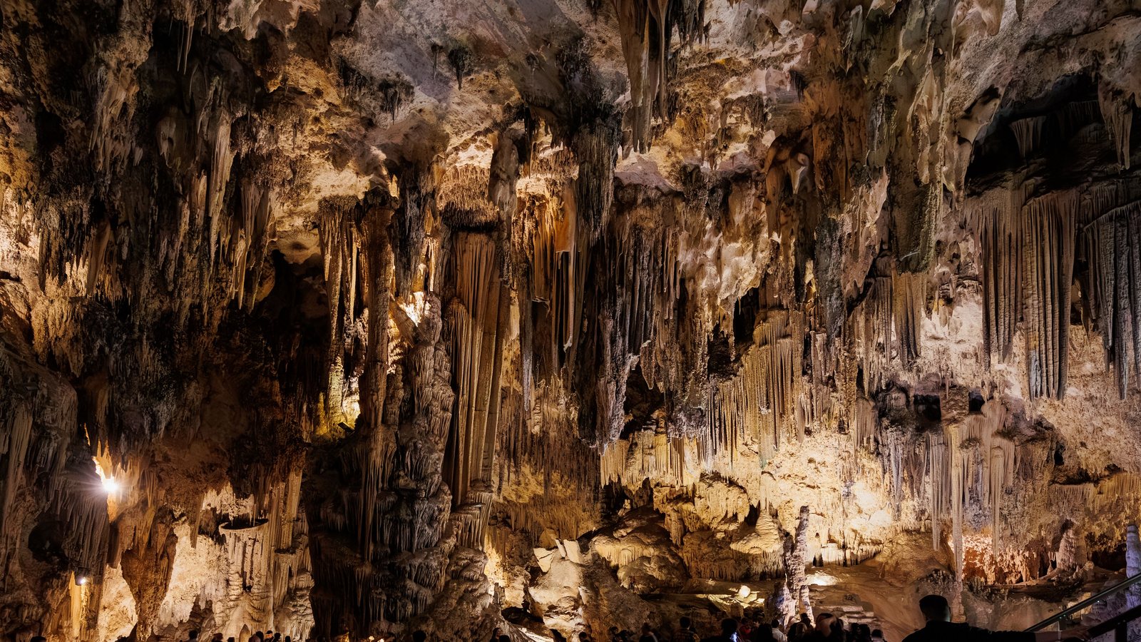 Beleuchtete Tropfsteinhöhle mit Besuchern auf einem Steg